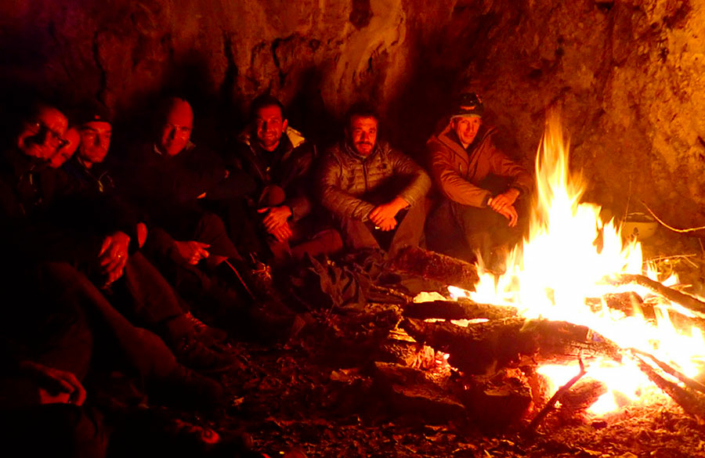 Groupe de personnes autour d'un feu de camps lors d'un stage de survie extrême